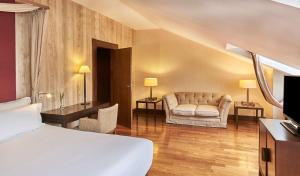 a hotel room with a bed and a couch at NH Collection Palacio de Burgos in Burgos