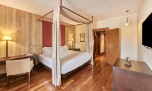 a bedroom with a bed and a desk and a television at NH Collection Palacio de Burgos in Burgos