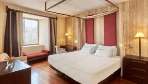 a hotel room with a large white bed and a chair at NH Collection Palacio de Burgos in Burgos +35 photos