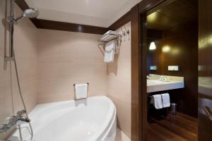 a bathroom with a white tub and a sink at NH Collection Palacio de Burgos in Burgos