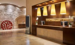 a lobby with a reception desk and a red chair at NH Collection Palacio de Burgos in Burgos