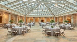 un salón de banquetes con mesas y sillas y techo de cristal en NH Collection Palacio de Burgos en Burgos