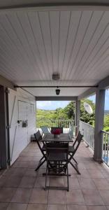 un patio con mesa y sillas en un porche en CHARMANT HAUT DE VILLA AVEC PISCINE PARTAGEE en Le Vauclin