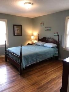 een slaapkamer met een bed en een houten vloer bij The KEMP’S BL ‘ONE in Fosters