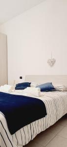 duże łóżko z niebiesko-białymi kocami i poduszkami w obiekcie San Siro House w Mediolanie