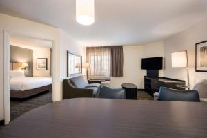 ヒューストンにあるSonesta Simply Suites Houston CityCentre I-10 Westのテーブルとベッドが備わるホテルルームです。