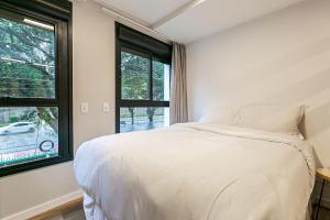 1 dormitorio con cama blanca y ventana en Studios completos no centro historico de Floripa proximo a diversos bares - HL Stay, en Florianópolis