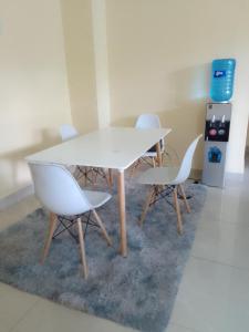 a white table and four chairs on a rug at Smarts residence in Nairobi