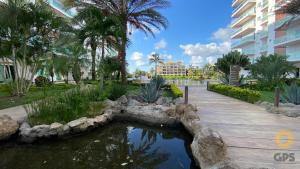 a pond in a park with palm trees and a building at 3010 Habitación en Pacifika, excelente ubicación in Mazatlán