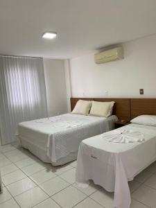 a hotel room with two beds with white sheets at Hotel Rota do Sertão in Serra Talhada