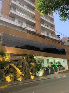un grand bâtiment avec un rocher devant un bâtiment dans l'établissement Apartamento Novissimo Aquarius II, à Poços de Caldas