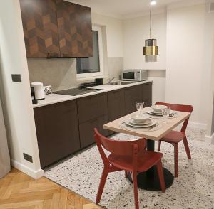 eine Küche mit einem Tisch und 2 Stühlen sowie eine Küche mit einem Waschbecken in der Unterkunft Falcon Apartment Center 1 Warszawa Centralna in Warschau