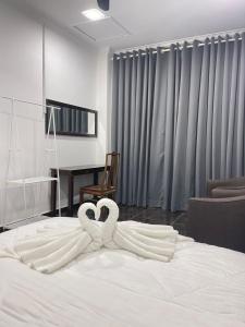 dois cisnes estão deitados em cima de uma cama em Aainaa Villa Homestay em Pasir Mas