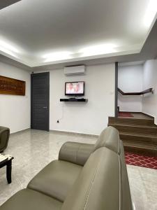 uma sala de estar com um sofá e uma televisão na parede em Aainaa Villa Homestay em Pasir Mas