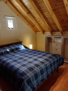 Un dormitorio con una cama de cuadros azules y techos de madera. en Cabaña La Encontrada en Villa Pehuenia