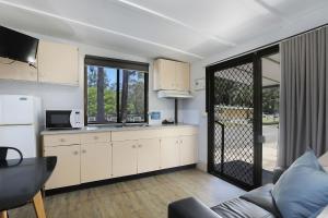 uma cozinha com um sofá, um frigorífico e uma mesa em Reflections Coffs Harbour - Holiday Park em Coffs Harbour