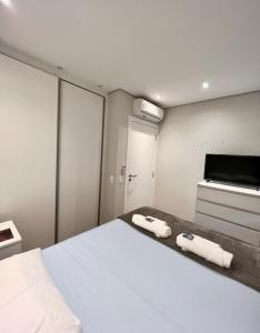 um quarto com uma cama branca com duas toalhas em 415 - Rentaqui - Flat Jardins Residence Confort em São Paulo