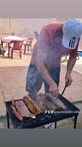 Um homem está a cozinhar carne numa grelha. em CASA CAMPESTRE LA ESMERALDA em Melgar