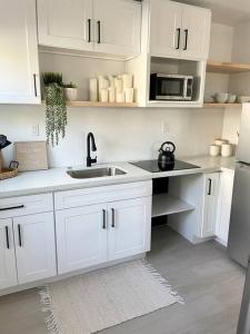a white kitchen with a sink and a microwave at Coastal inspired apartment in downtown culver city in Los Angeles