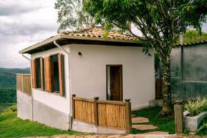 a small white house with a wooden fence at Pousada Monttana - By UP Hotel in Lavras Novas