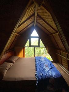 a bed in a small room with a window at Tetebatu Sama Sama Bungalows in Tetebatu