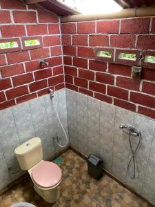 a bathroom with a toilet and a brick wall at Tetebatu Sama Sama Bungalows in Tetebatu