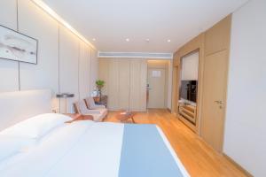 a bedroom with a white bed and a living room at Home Plus Hotel in Suzhou
