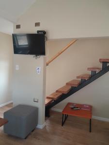 a living room with a staircase with a flat screen tv at EL RINCON DE LÚ in Chile Chico