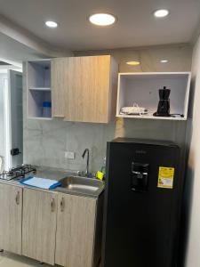 a kitchen with a black refrigerator and a sink at SWEET BREEZE in San Andrés