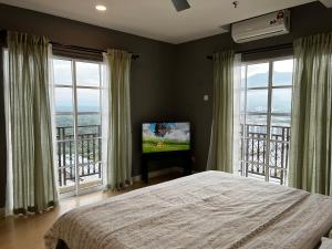 a bedroom with a bed and a television with windows at Netflix l Chill Studio Kampar Champs Élysées in Kampar