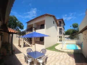 a patio with a table and an umbrella and a pool at Pousada Cabufa in Cabo Frio