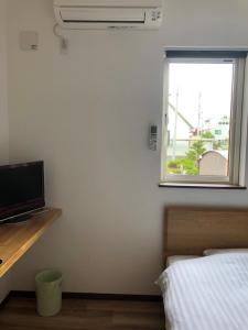a bedroom with a bed and a television and a window at Minshuku Cress in Biei