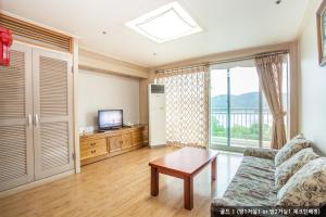 a living room with a couch and a table and a television at Gyeongju Ilsung Condo in Gyeongju