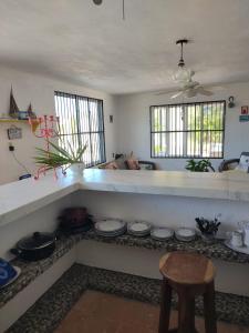 uma cozinha com um balcão com pratos e um banco em Casa Ibiza Celestun em Celestún