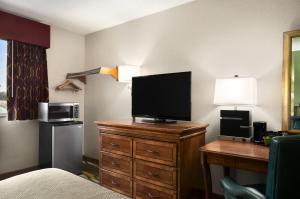 una habitación de hotel con TV en un tocador con escritorio en Travelodge by Wyndham Battle Creek, en Battle Creek