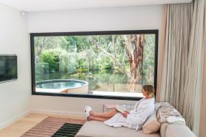 Eine Frau, die vor einem Fenster auf einer Couch sitzt. in der Unterkunft Beresford Estate in McLaren Flat