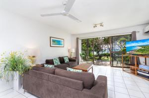 a living room with two couches and a tv at Seascape Holidays at Beachfront Terraces in Port Douglas