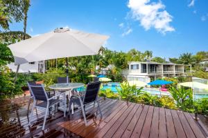 a deck with a table and chairs and an umbrella at Seascape Holidays at Beachfront Terraces in Port Douglas