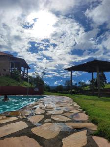 une passerelle en pierre à côté d'une piscine avec ciel ouvert dans l'établissement Chalés Bela Vista, à São Thomé das Letras
