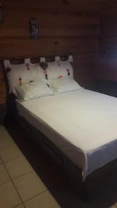 uma cama com lençóis brancos e almofadas num quarto em Yatzil em La Trinitaria