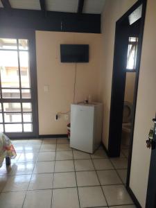 um quarto com um pequeno frigorífico e uma televisão na parede em Vô Doríbio em Torres