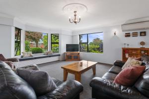 a living room with leather couches and a coffee table at Little Big House - Rotorua Holiday Home in Rotorua