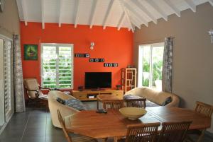 uma sala de estar com uma mesa e uma televisão em Villa avec piscine em Sainte-Anne