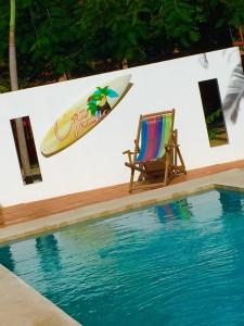 una silla y una tabla de surf en una pared junto a una piscina en Cote Pacific Casitas, en Huacas