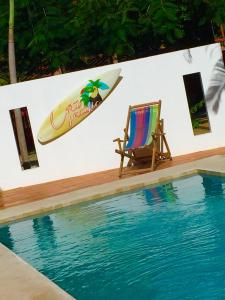 a chair and a surfboard on a wall next to a swimming pool at Cote Pacific Casitas in Huacas