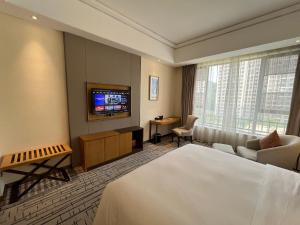 広州市にあるGuangzhou Nanhong Ausotel Hotelのベッドとテレビが備わるホテルルームです。