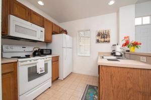 a kitchen with white appliances and wooden cabinets at Pet Friendly House in Resort Style Condo Near Disney, 4 Pools, Hot Tub & Gym in Kissimmee