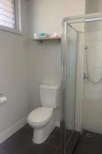 a bathroom with a toilet and a glass shower at The Cavenagh in Darwin