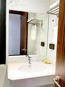 ein weißes Badezimmer mit einem Waschbecken und einem Spiegel in der Unterkunft A25 Hotel - 187 Trung Kính in Hanoi