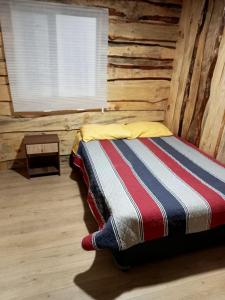 a bed in a log cabin with a window at Cabaña Cunco parcela in Cunco
